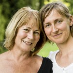 Two women standing outside, smiling. 